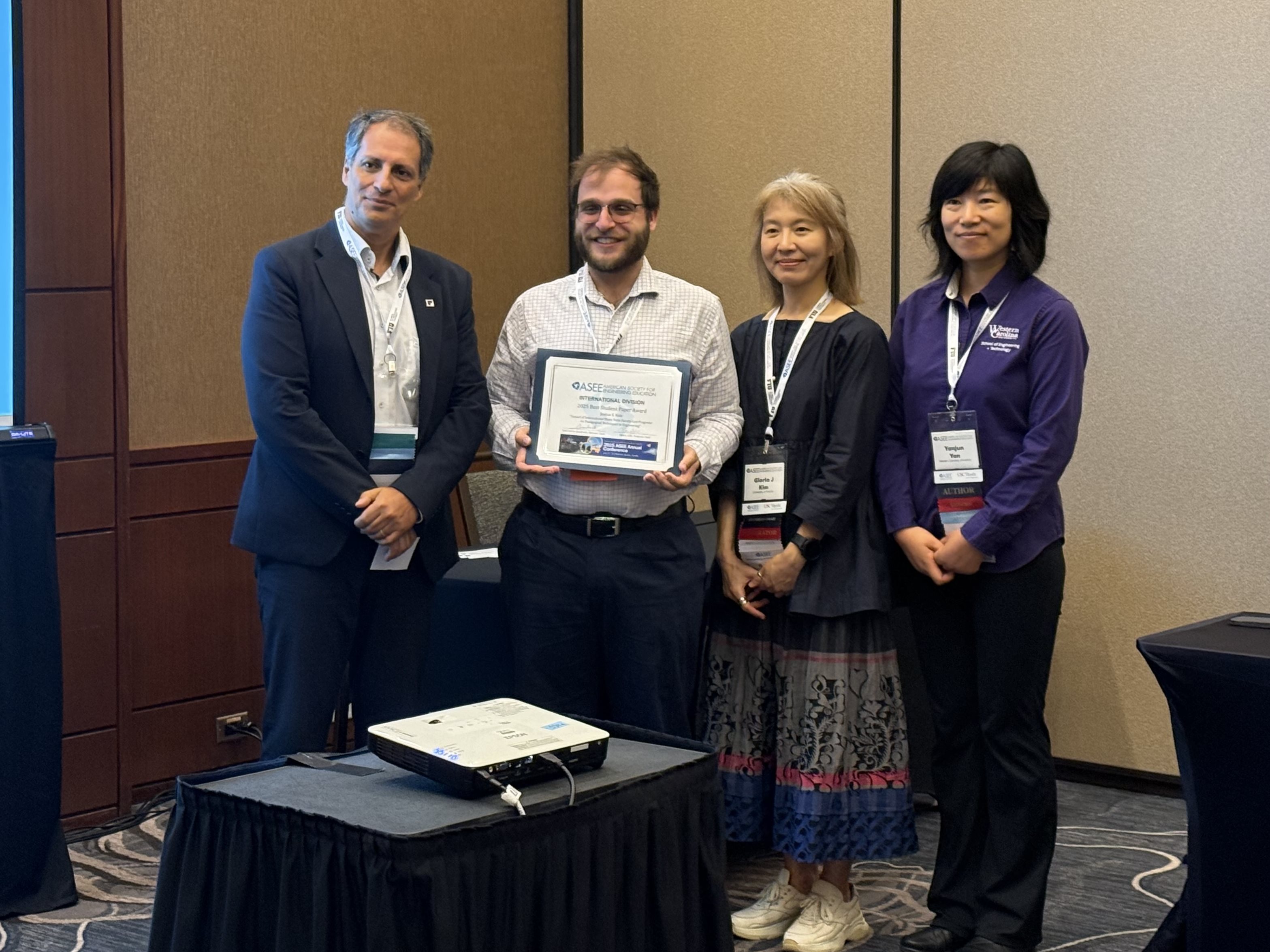 graudate student josh katz posing with three people and holding an award