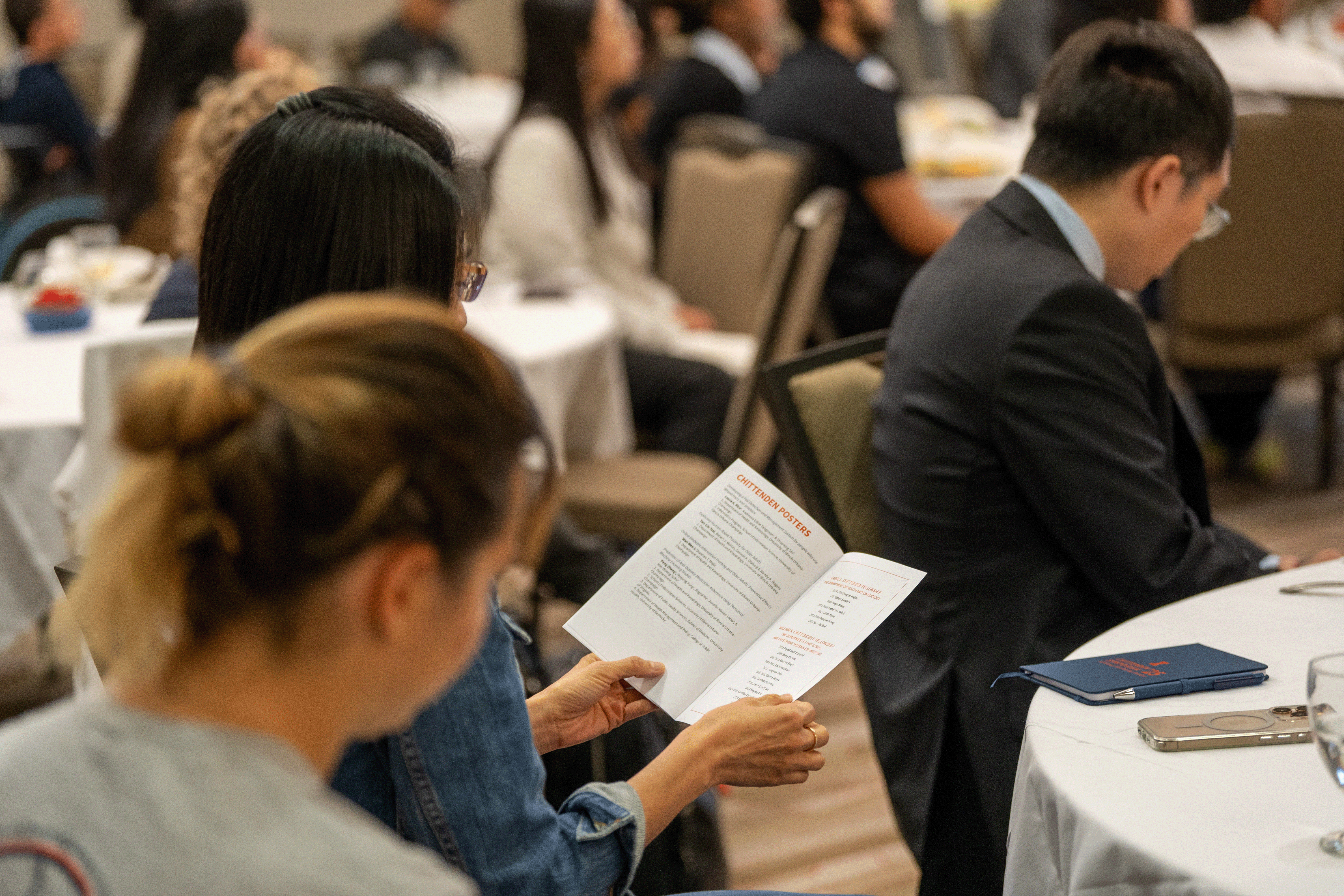 event attendee looking at the program seated at a table