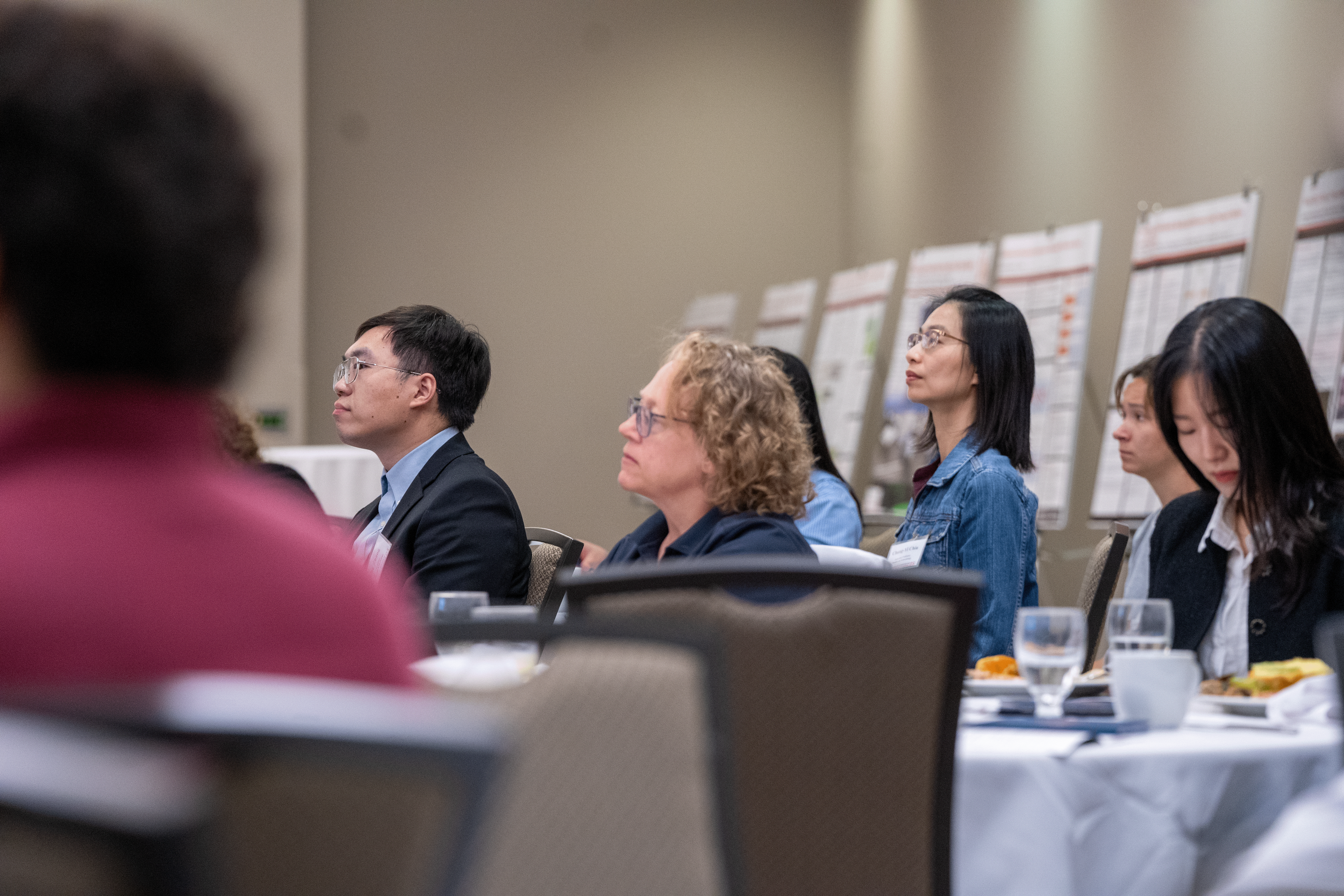 people sitting at a table listening to a presentation