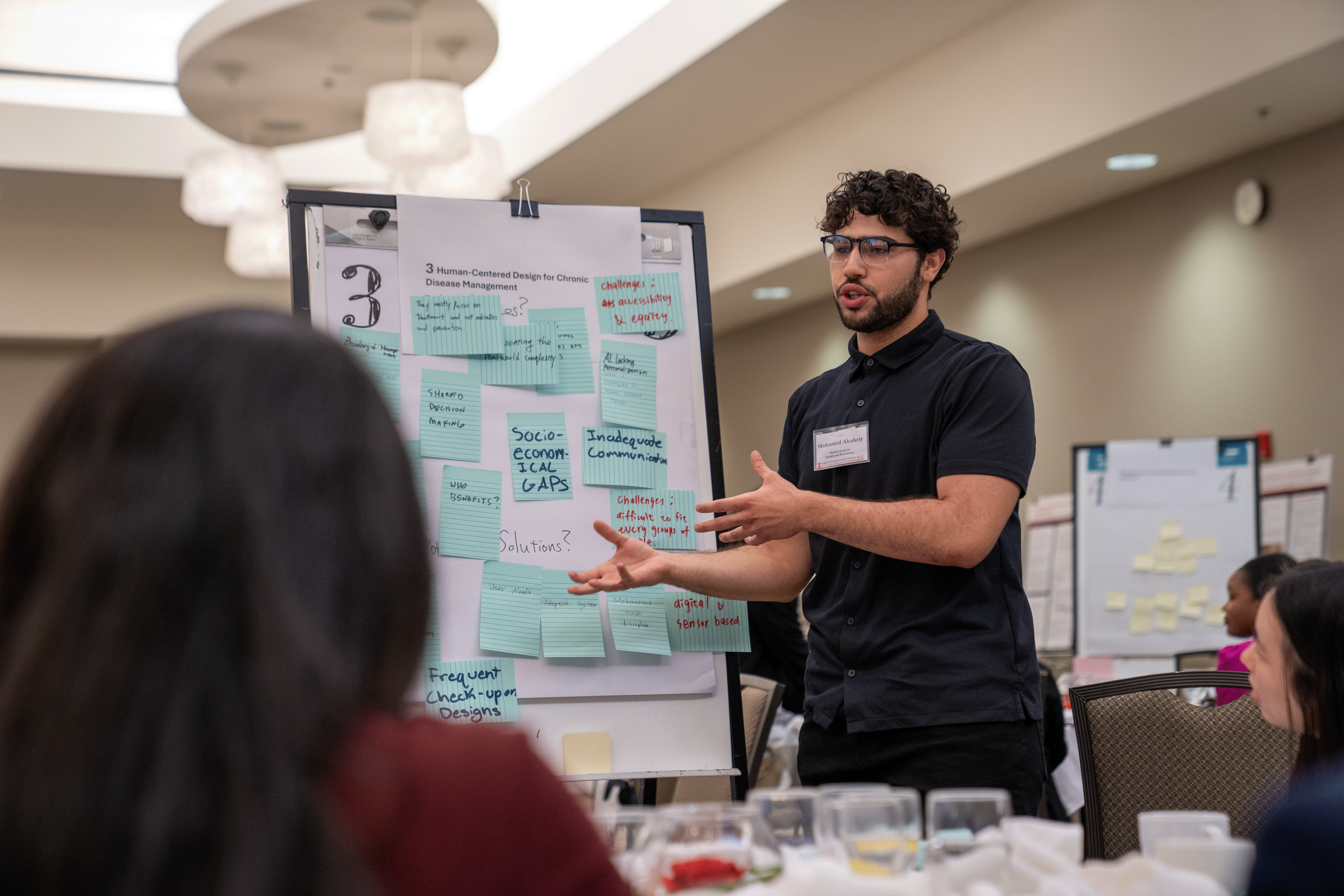 ise student presents at a white board with post its filled with writing.