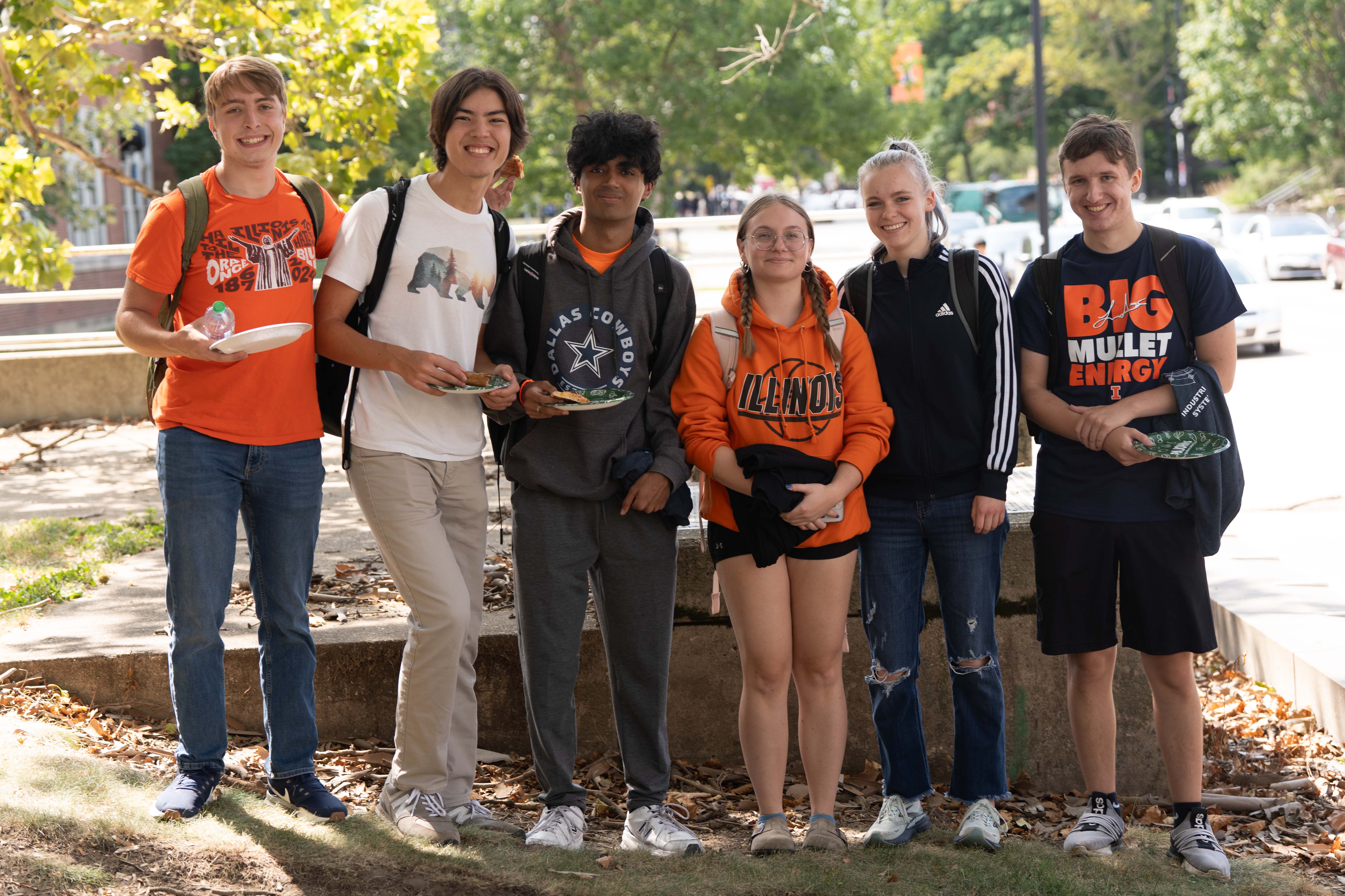 6 students standing in a line outside the Transportation Building. They are attending the welcome week pizza party.