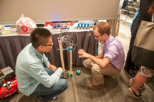 MechSE Master&rsquo;s student Xiaotian Zhang describes his creation to a curious onlooker.