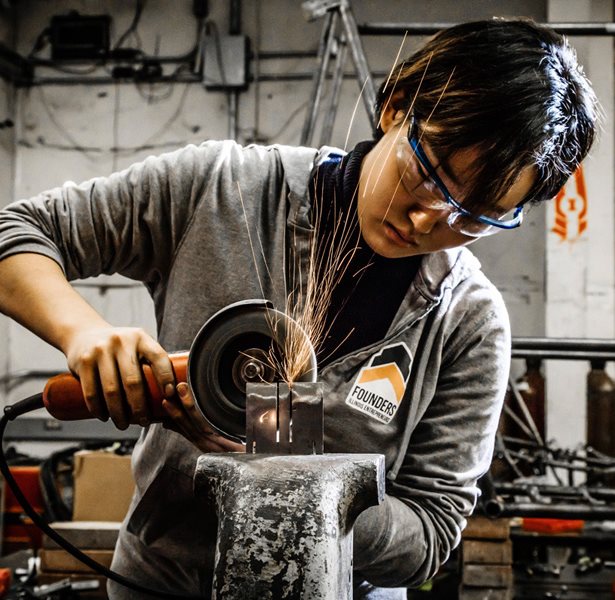 Sparks fly as student uses saw on metal